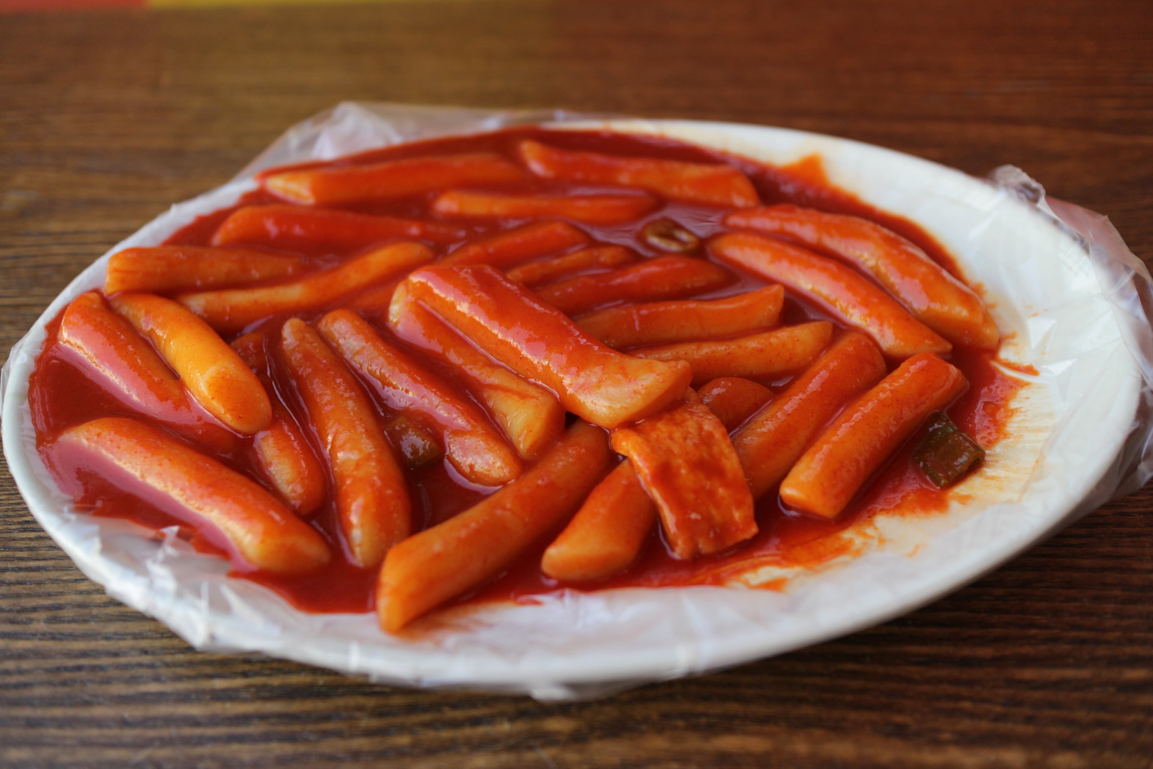 A plate of Korean tteokbokki with red spicy sauce and rice cakes.