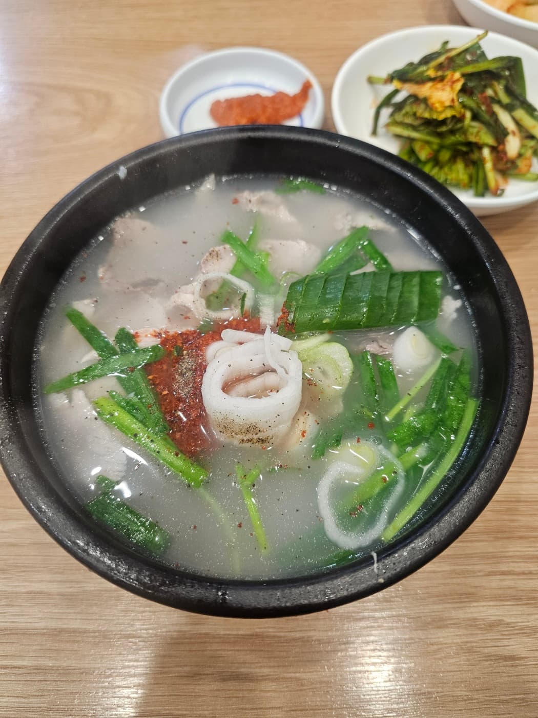 Close-up of dwaeji gukbap with pork, green onions, and seasoning