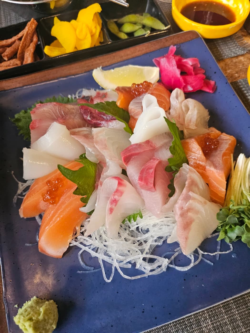 A plate of assorted sashimi served with side dishes