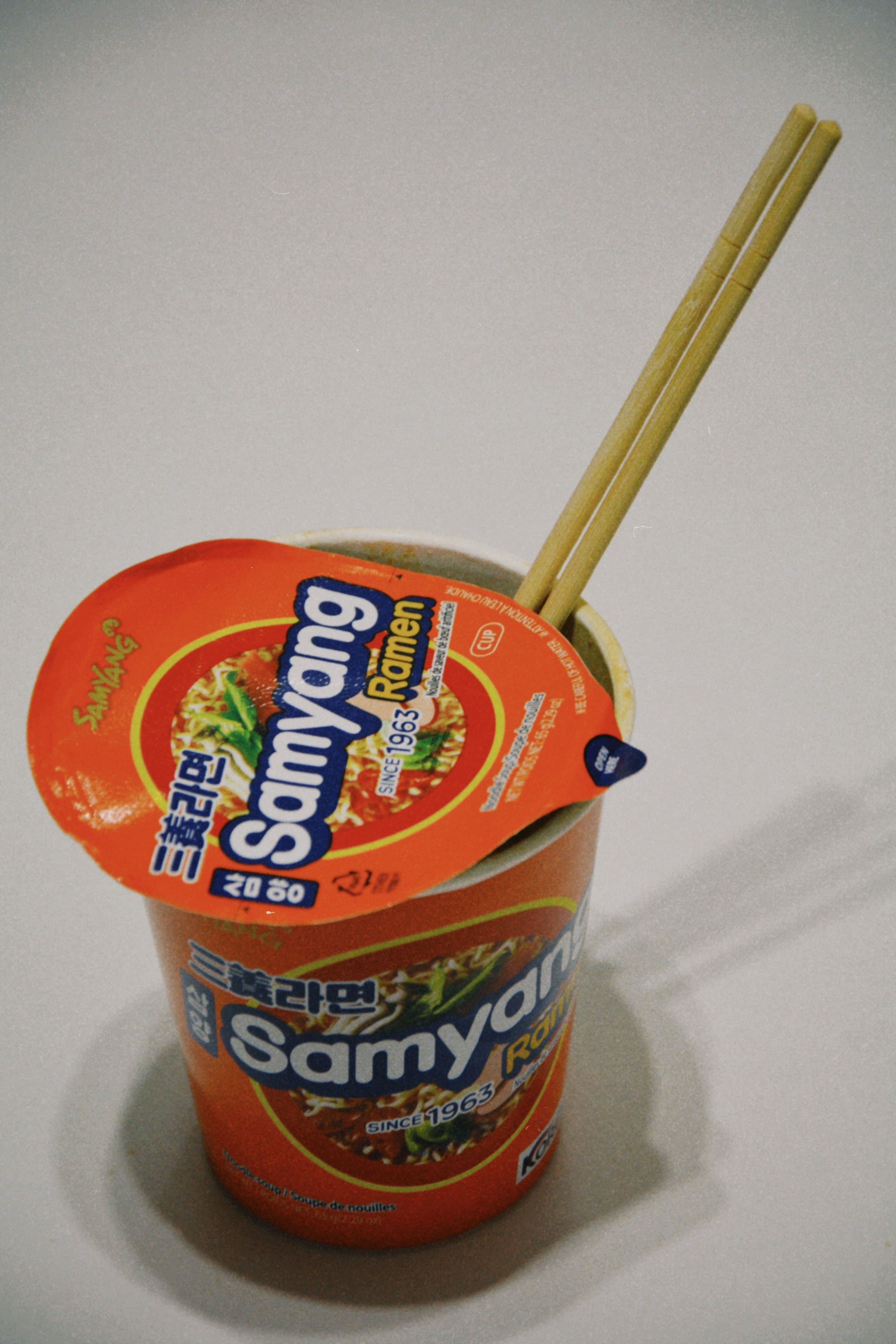 A Korean cup ramyeon with chopsticks, shown as an example of convenience store cup noodles.